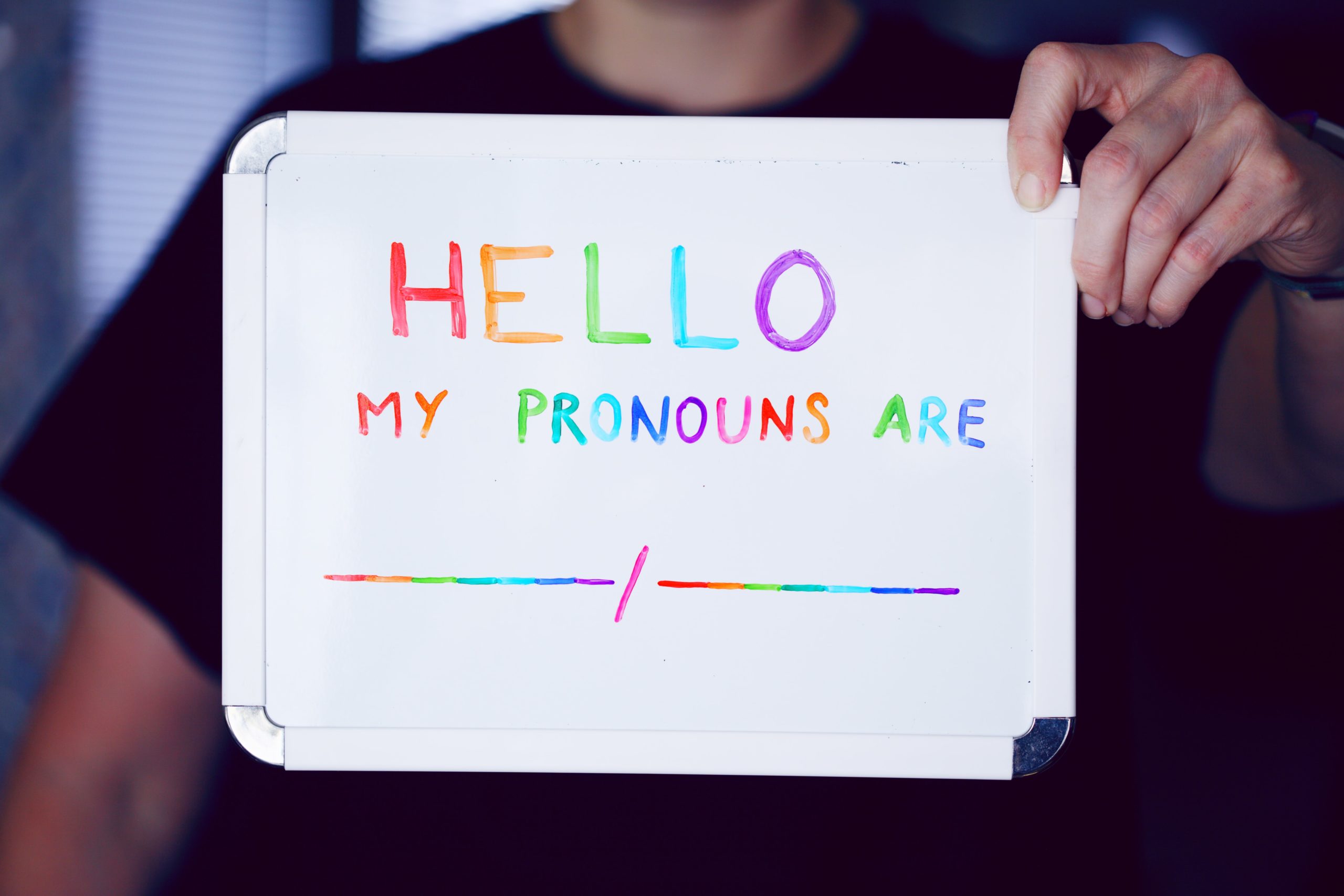 Person hält Schild "Hello, My Pronouns are _/_"
